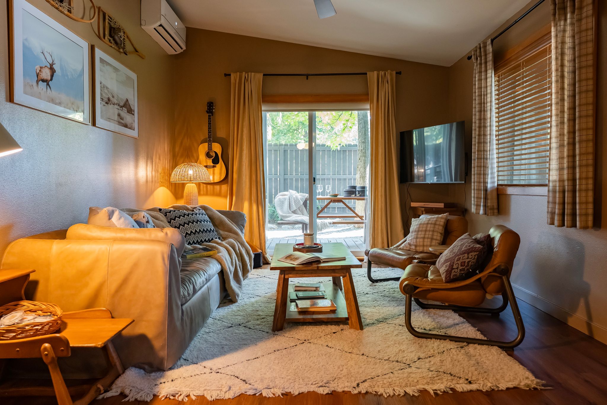 Living room with leather sofa, guitar wall and sliding door to the deck