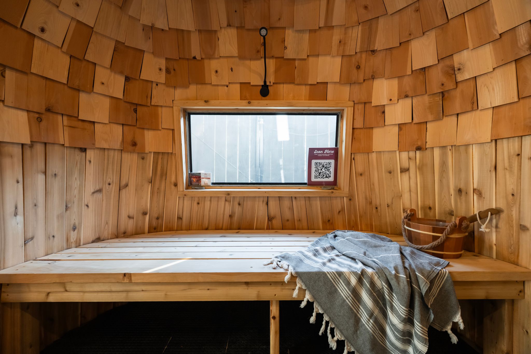 Sauna bench under the window with cedar shingle ceiling