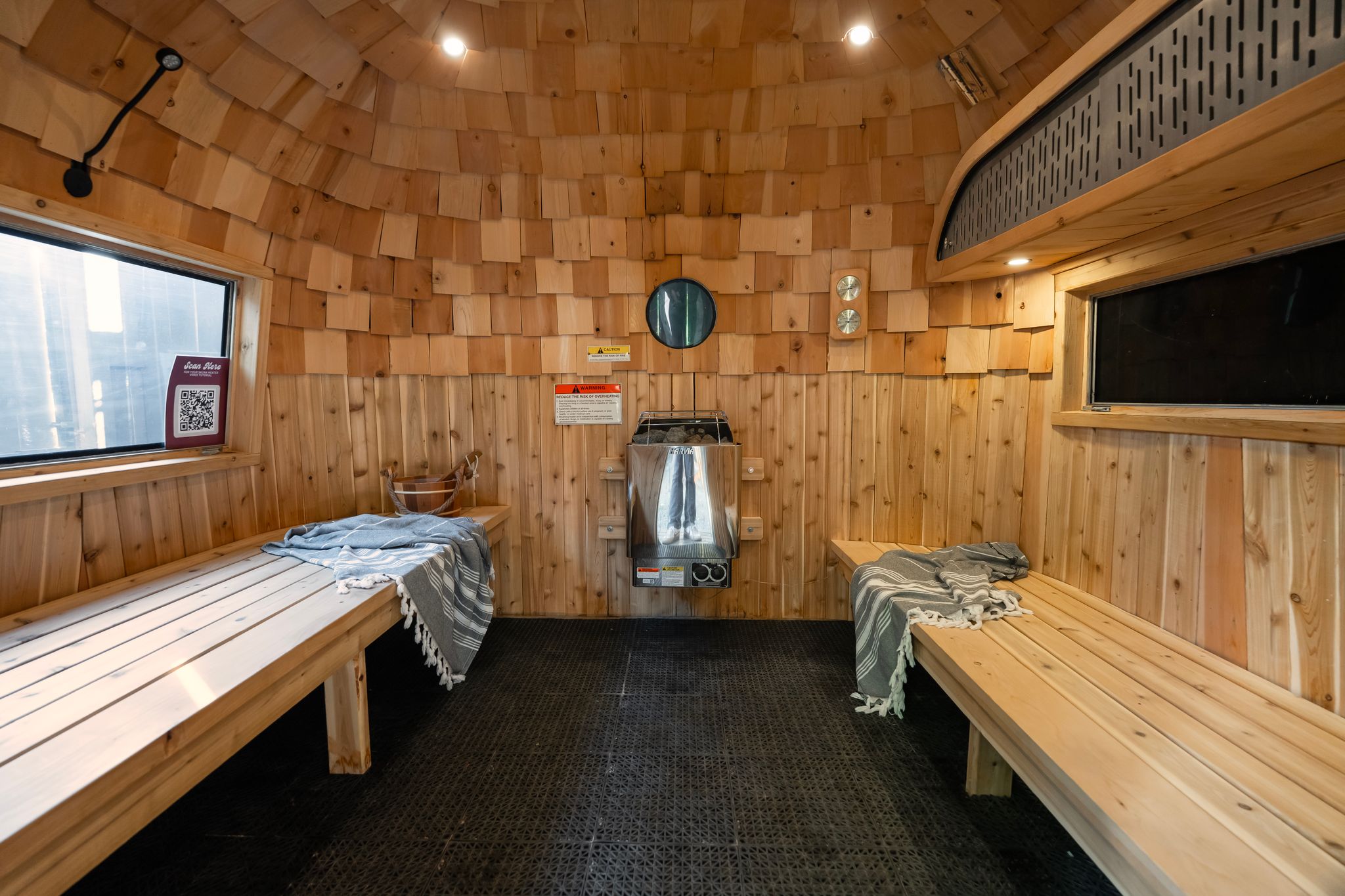Cedar sauna interior with two benches, Harvia heater and porthole window