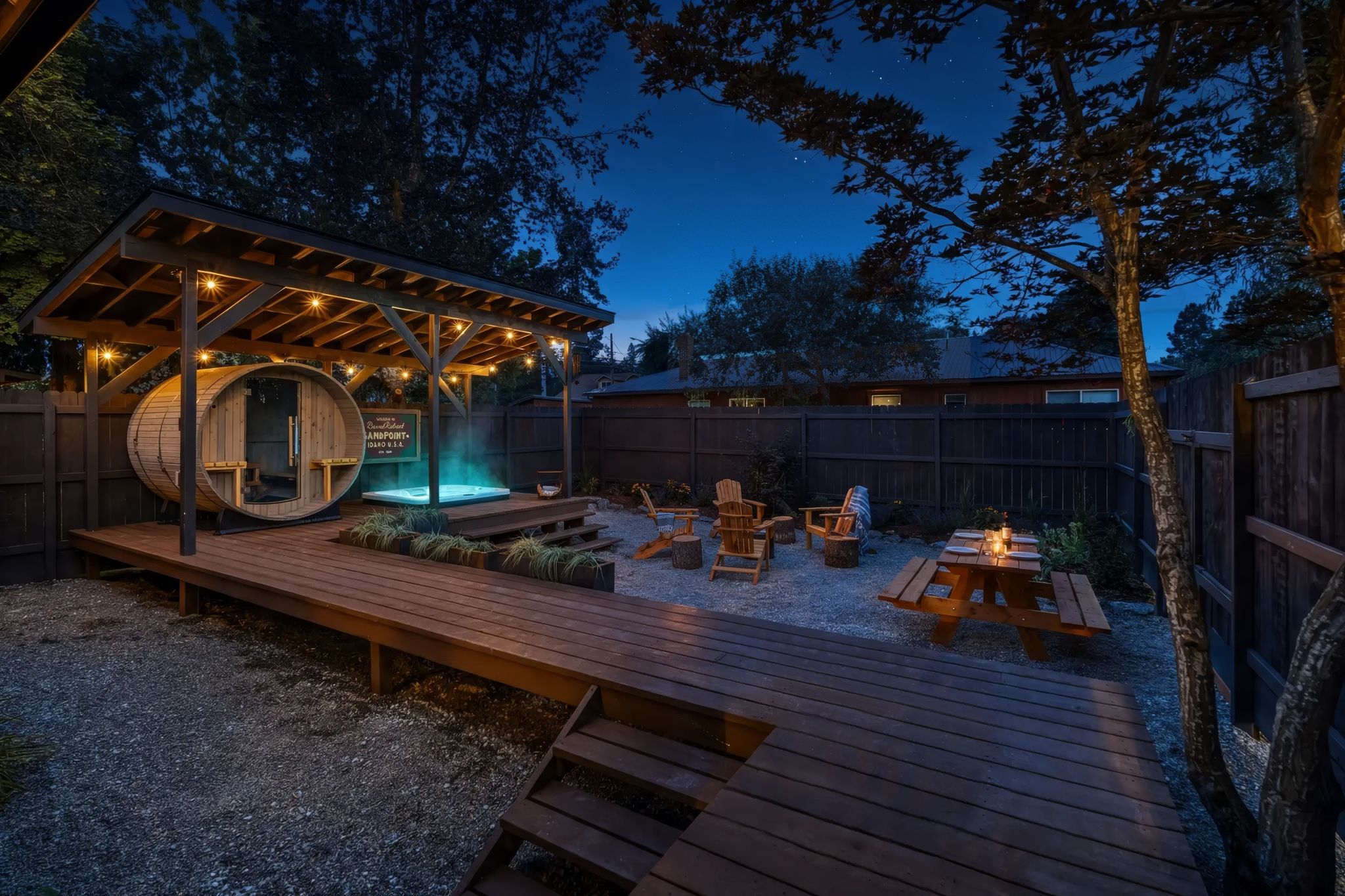Backyard at night with covered sauna, hot tub, fire pit, and picnic table