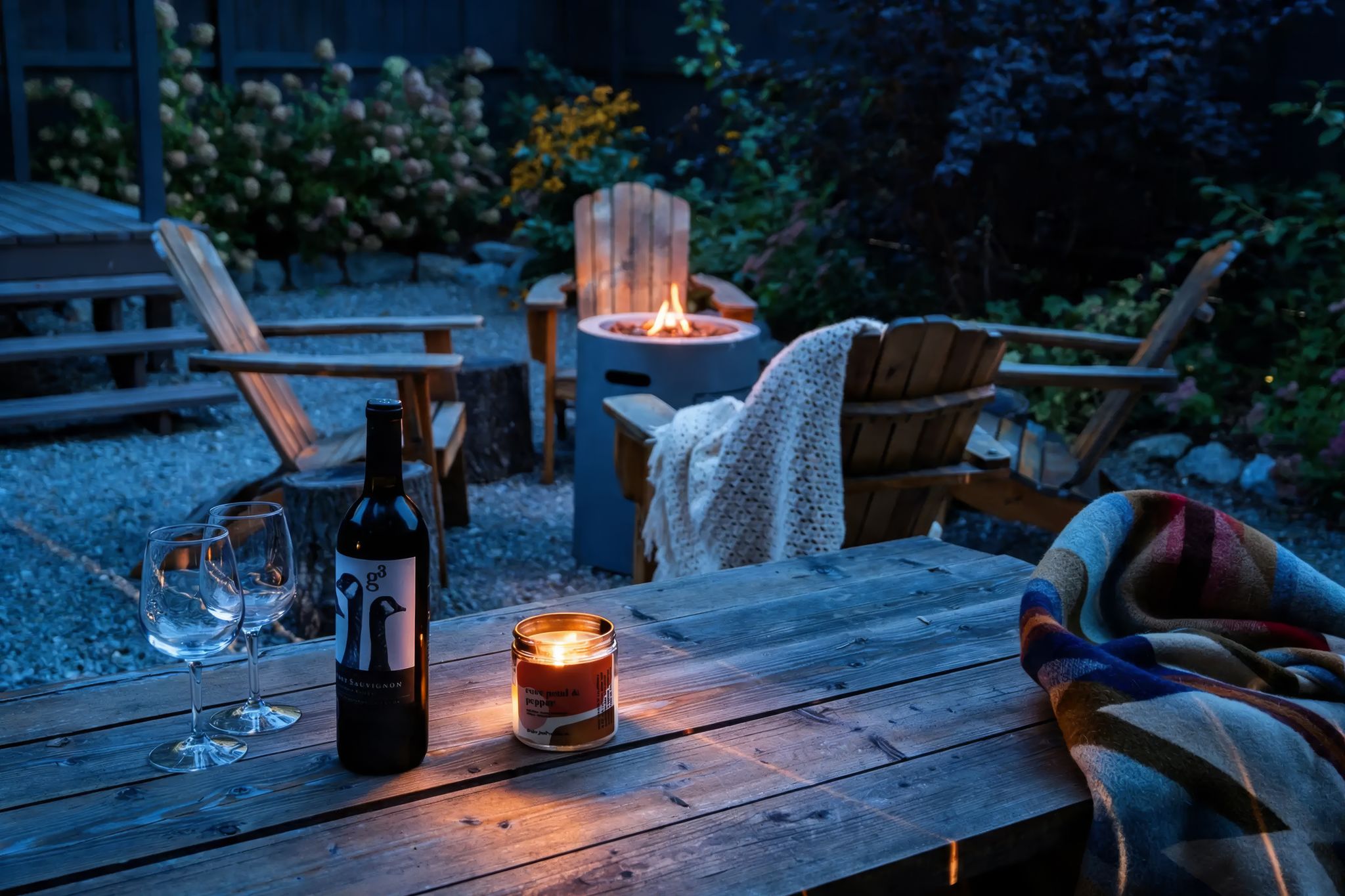 Wine, candle, and Pendleton blanket by the fire pit at dusk