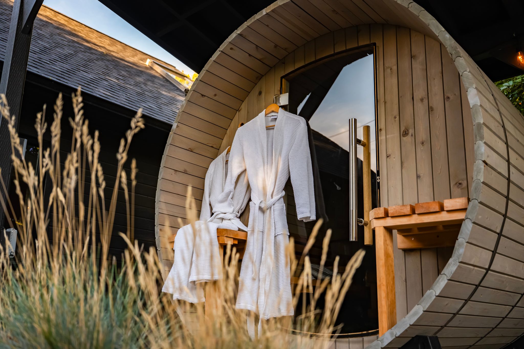 Cedar barrel sauna with waffle robe at golden hour