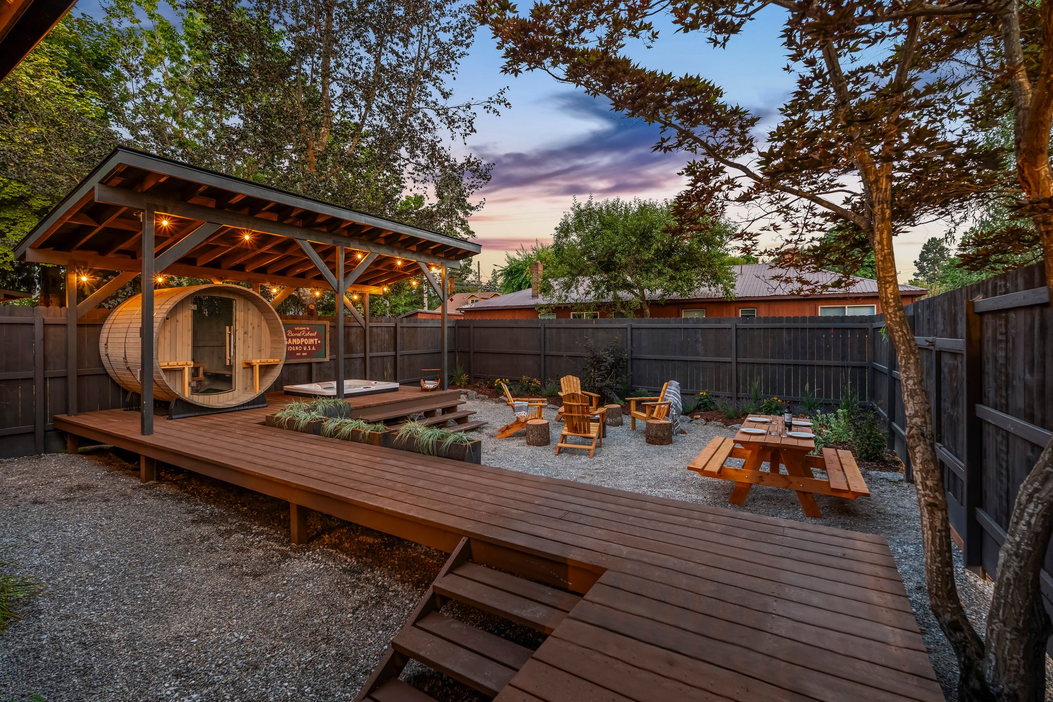 Barrel sauna and outdoor deck at sunset with string lights